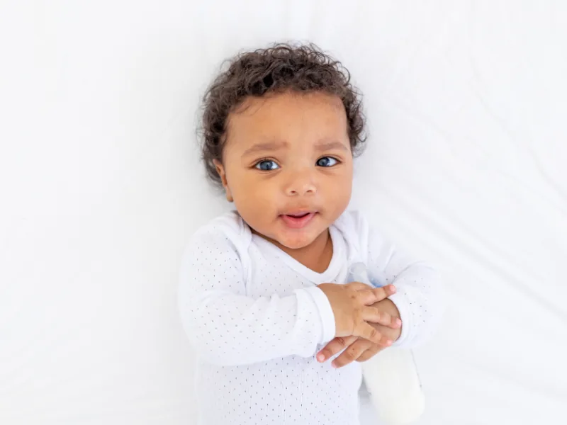 Smiling infant playing on a mat at Mandy's Learning Academy